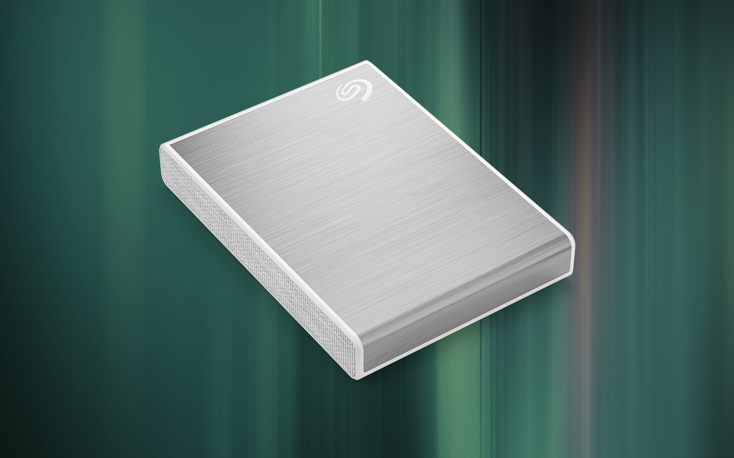 Brushed silver external Seagate SSD for gaming lays at an angle over an abstract green background.
