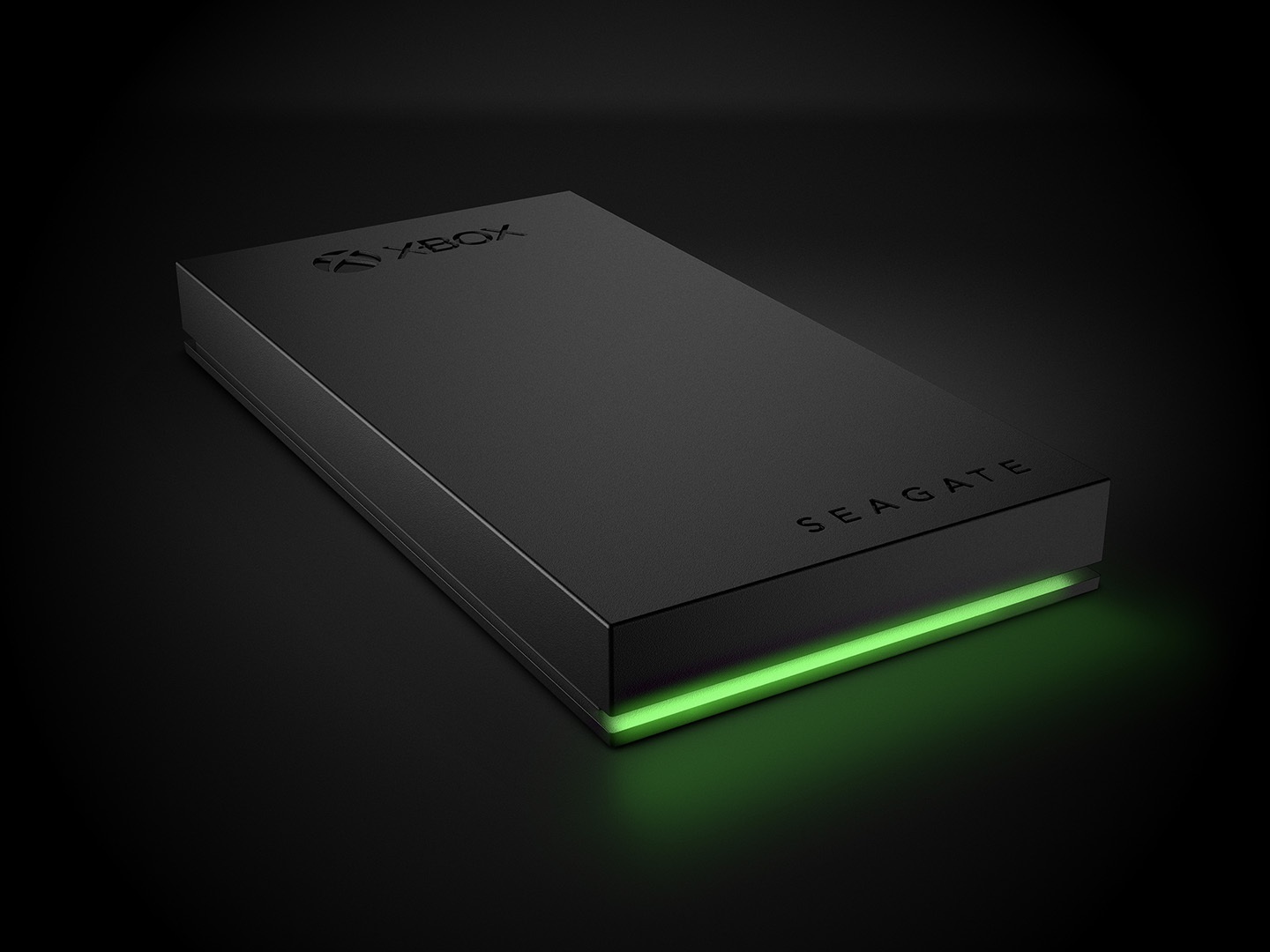 Seagate Game Drive for Xbox lays flat angled to the right, featuring the Xbox and Seagate logos and glowing green light.