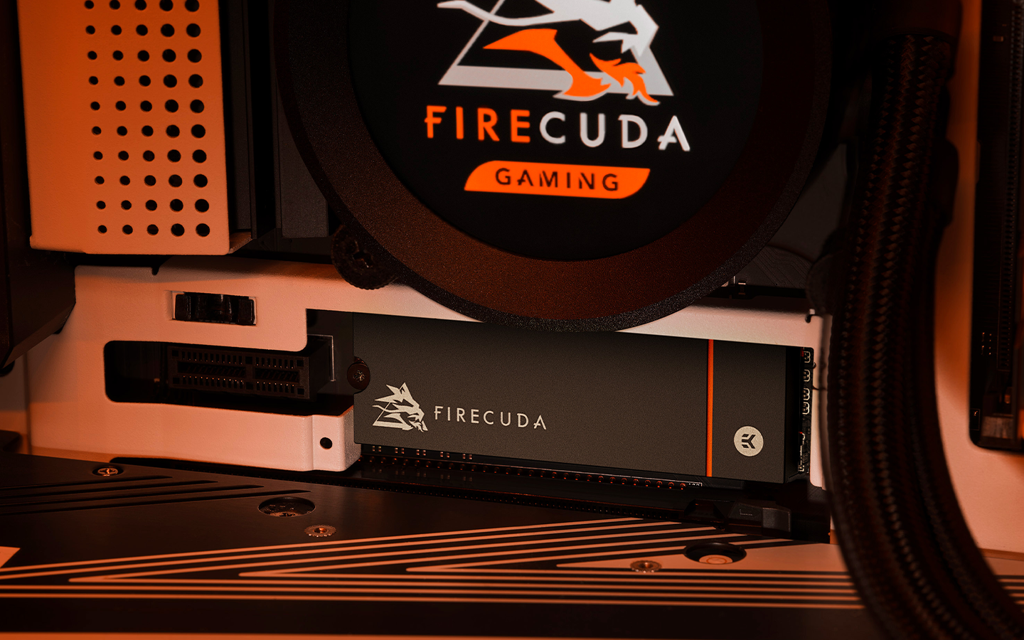 FireCuda liquid cooler mounted on a PC motherboard sits above a FireCuda NVMe SSD installed in the M.2 slot.