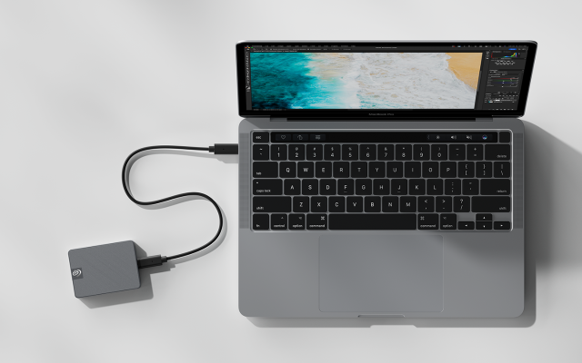 Overhead image of a laptop connected to a Seagate portable SSD shows its compact size in comparison.