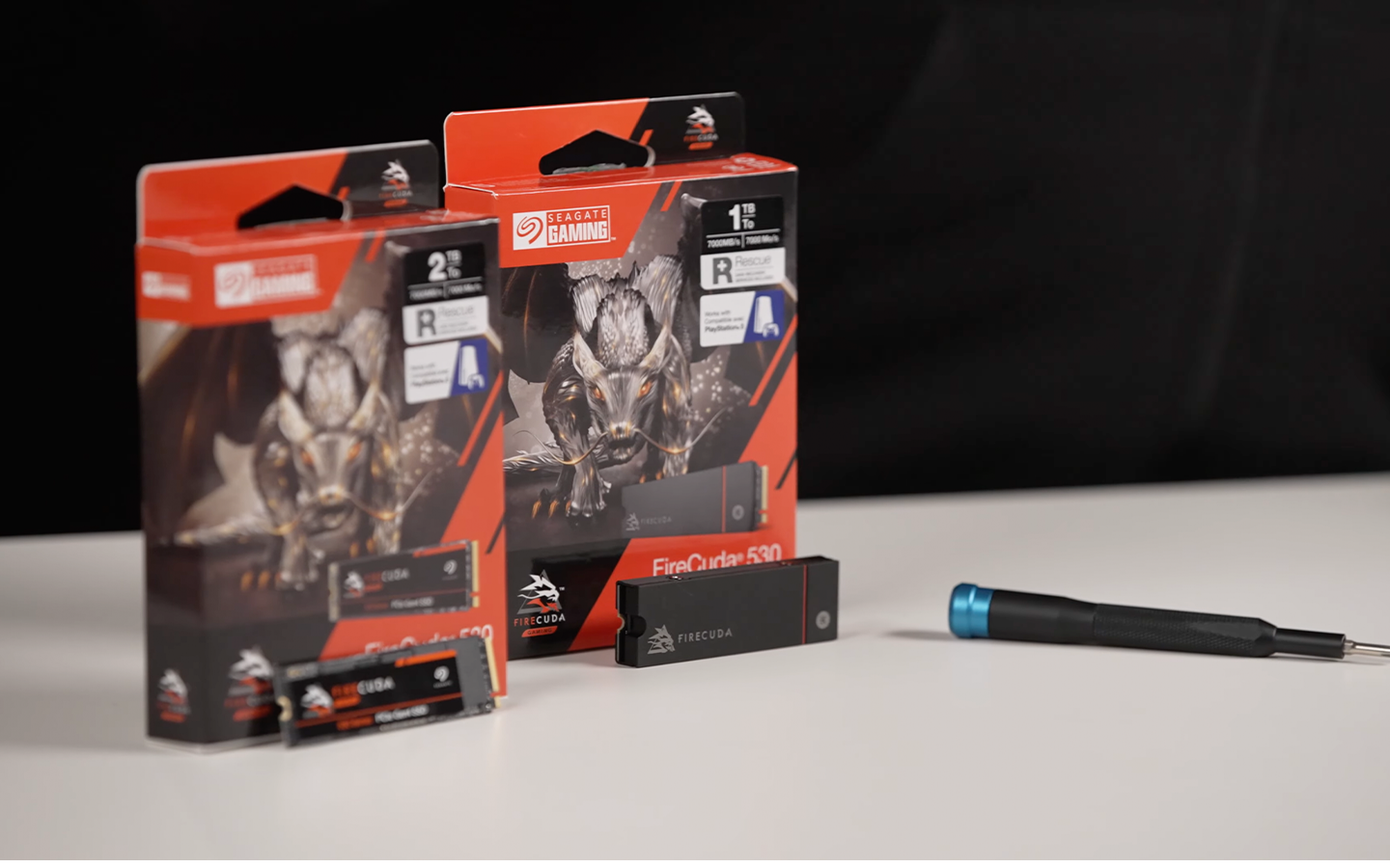 Two Seagate game drives stand in front of product packaging and next to a screwdriver.