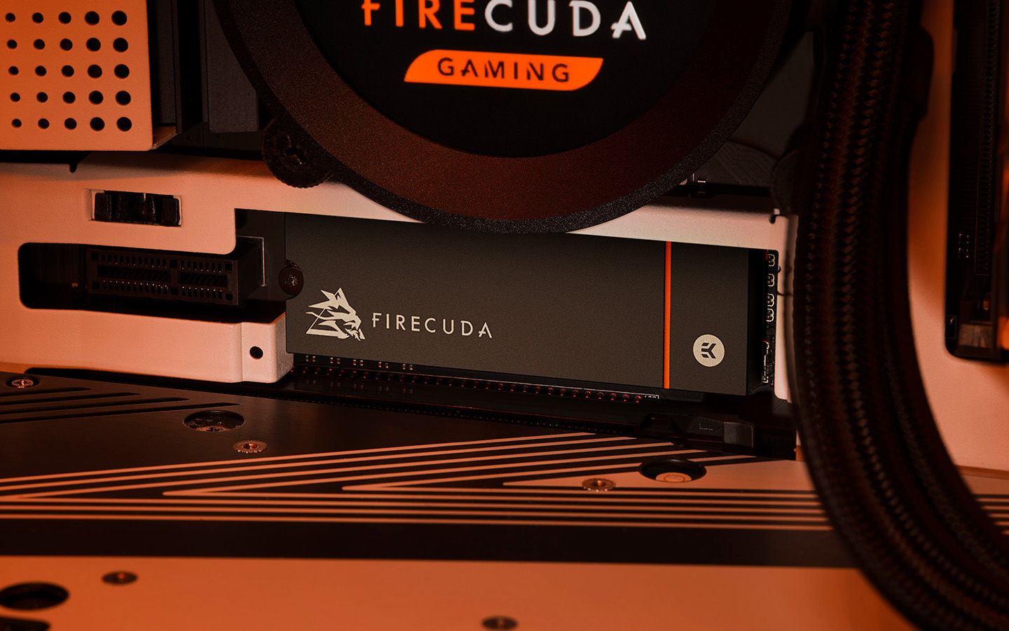 FireCuda Gaming drive installed inside a desktop computer, is illuminated by orange case lighting and surrounded by internal hardware.