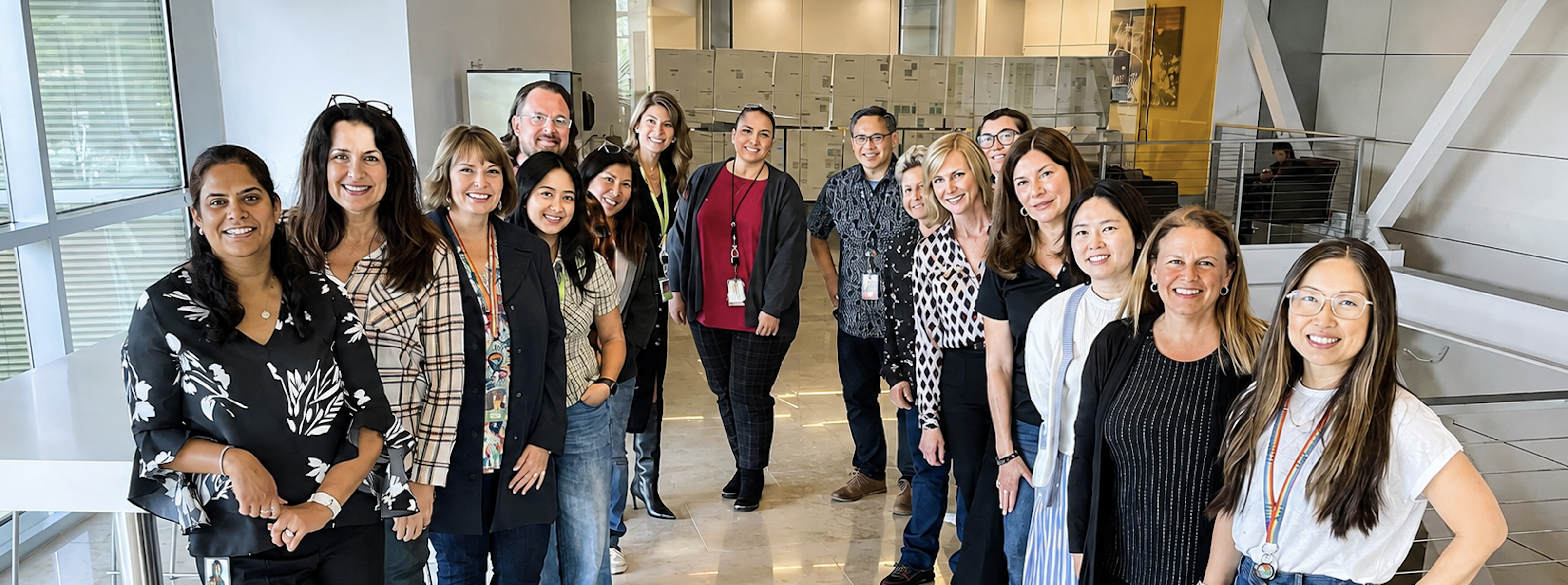 Group of employees stand together and smile in an office corridor.