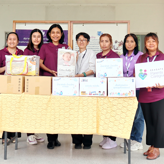 Seven people stand behind a table with donated supplies for a community giving initiative. 