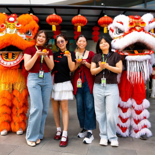Four Seagate employees pose with lion dance performers during a Lunar New Year celebration. 