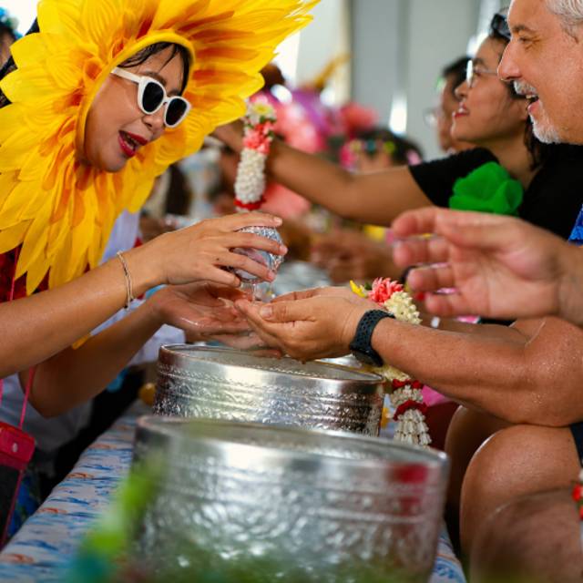 Participants gather around a Songkran activity that highlights community and shared experiences. 