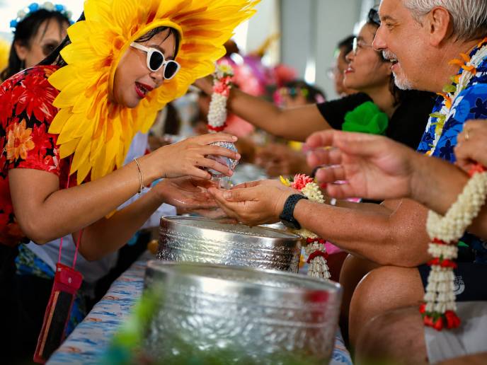 Participants gather around a Songkran activity that highlights community and shared experiences. 