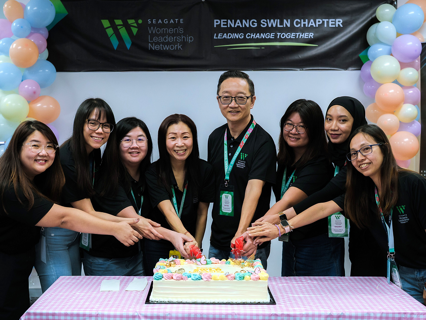 Team members gather around a decorated cake during a Women’s Leadership Network chapter celebration. 