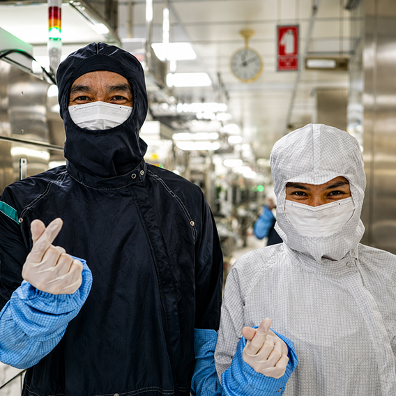 Two Seagate employees wearing cleanroom protective gear in a manufacturing facility.