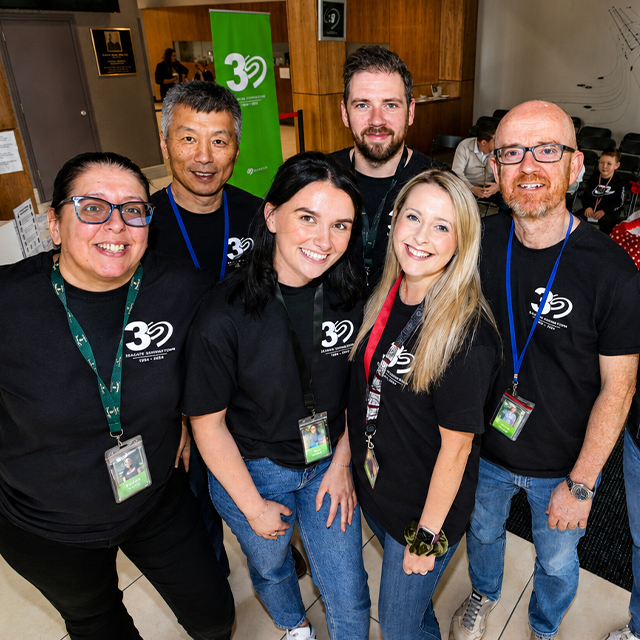 Group of employees wearing matching shirts pose together for a team photo. 