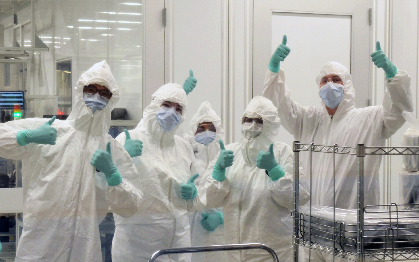 Seagate manufacturing employees wearing cleanroom protective gear and giving thumbs up.