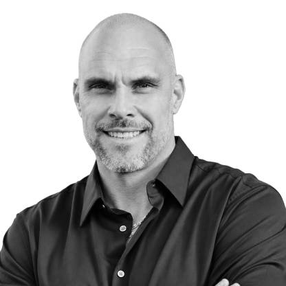 Black-and-white headshot of Mike Kulich with a shaved head and short beard, wearing a dark button-down shirt, facing the camera.