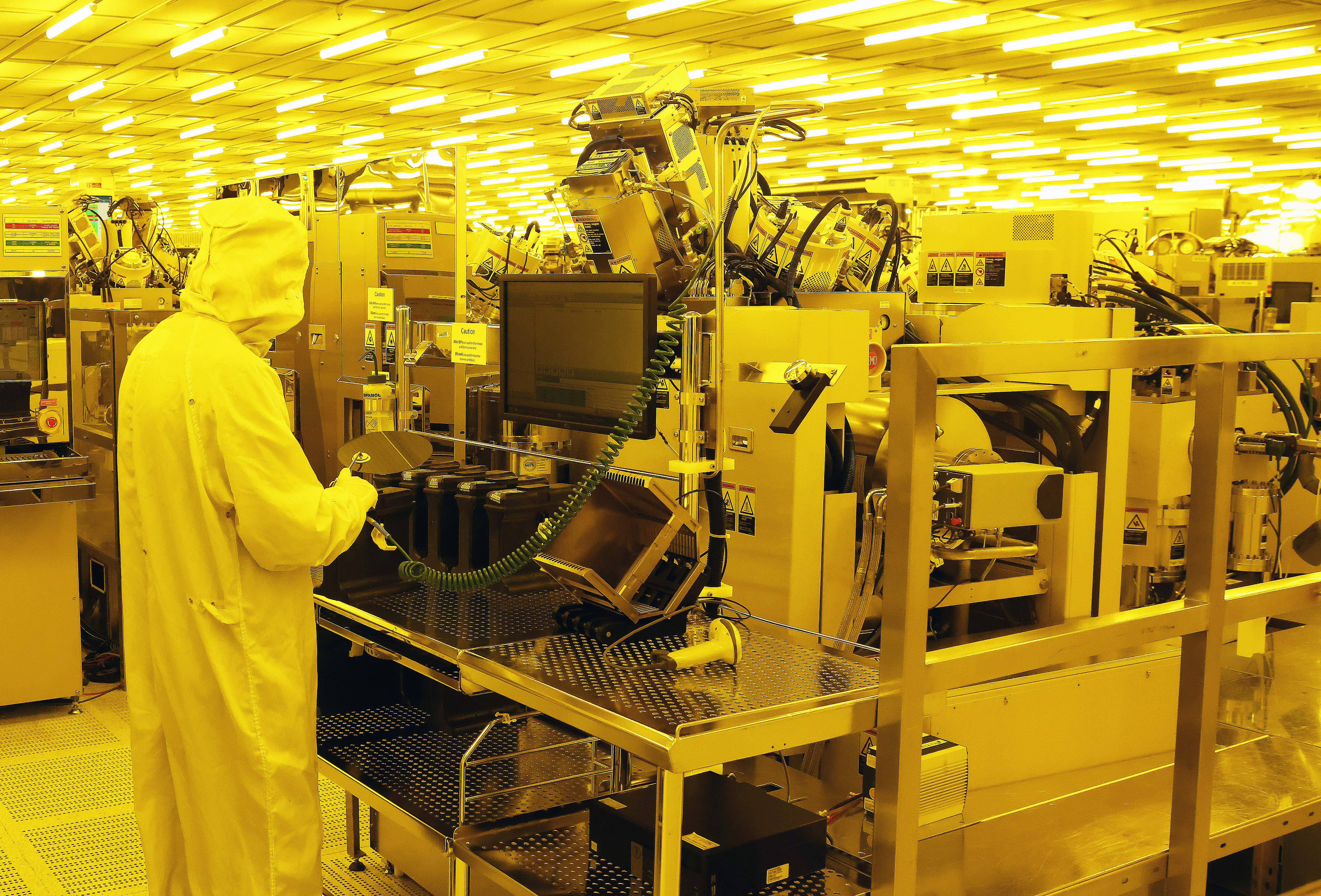 Een persoon in een cleanroom die beschermende kleding draagt, werkt met elektronische apparatuur in een fabriek in Noord-Ierland.