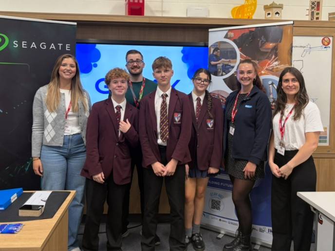 Three students in school uniforms stand with Seagate employees in front of classroom as part of a STEM career information-sharing event.
