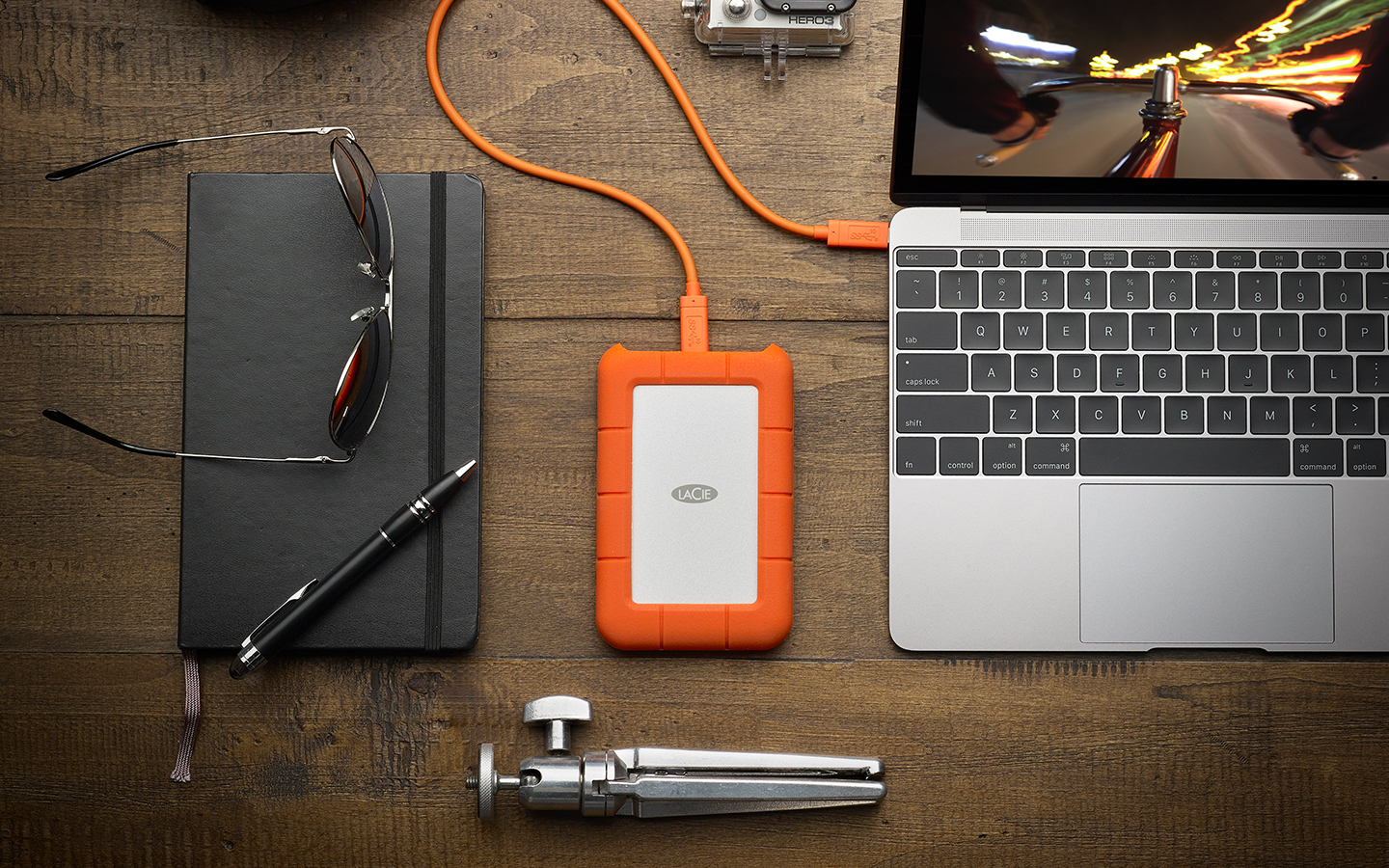 Laptop with LaCie Rugged Secure drive, GoPro, backpack, and gear suggests a portable setup for video editing on the go.
