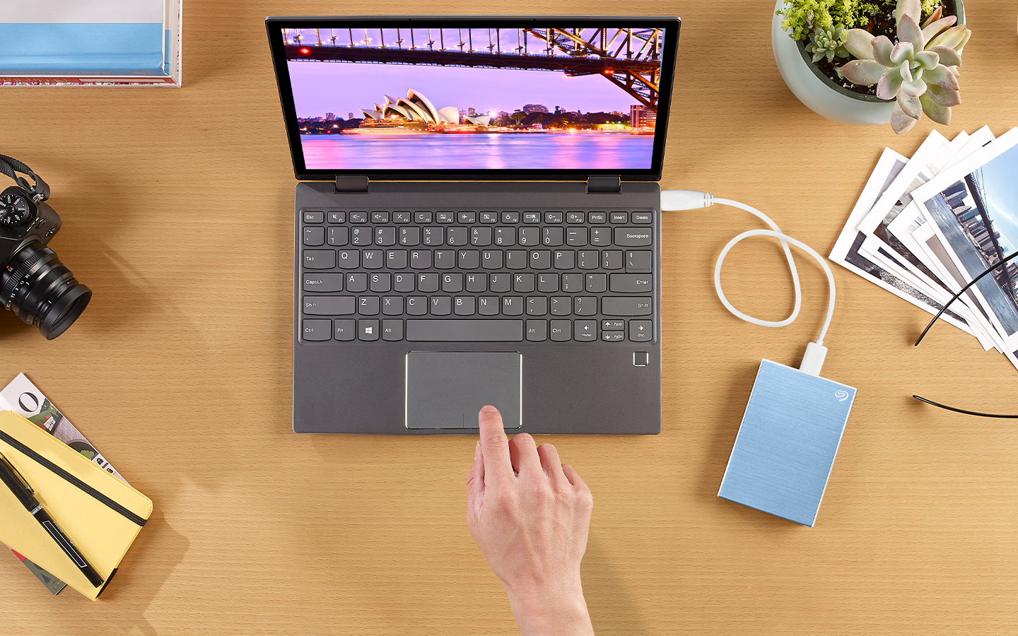 Mac laptop connected to a Seagate One Touch portable hard drive is surrounded by a camera and printed photos.